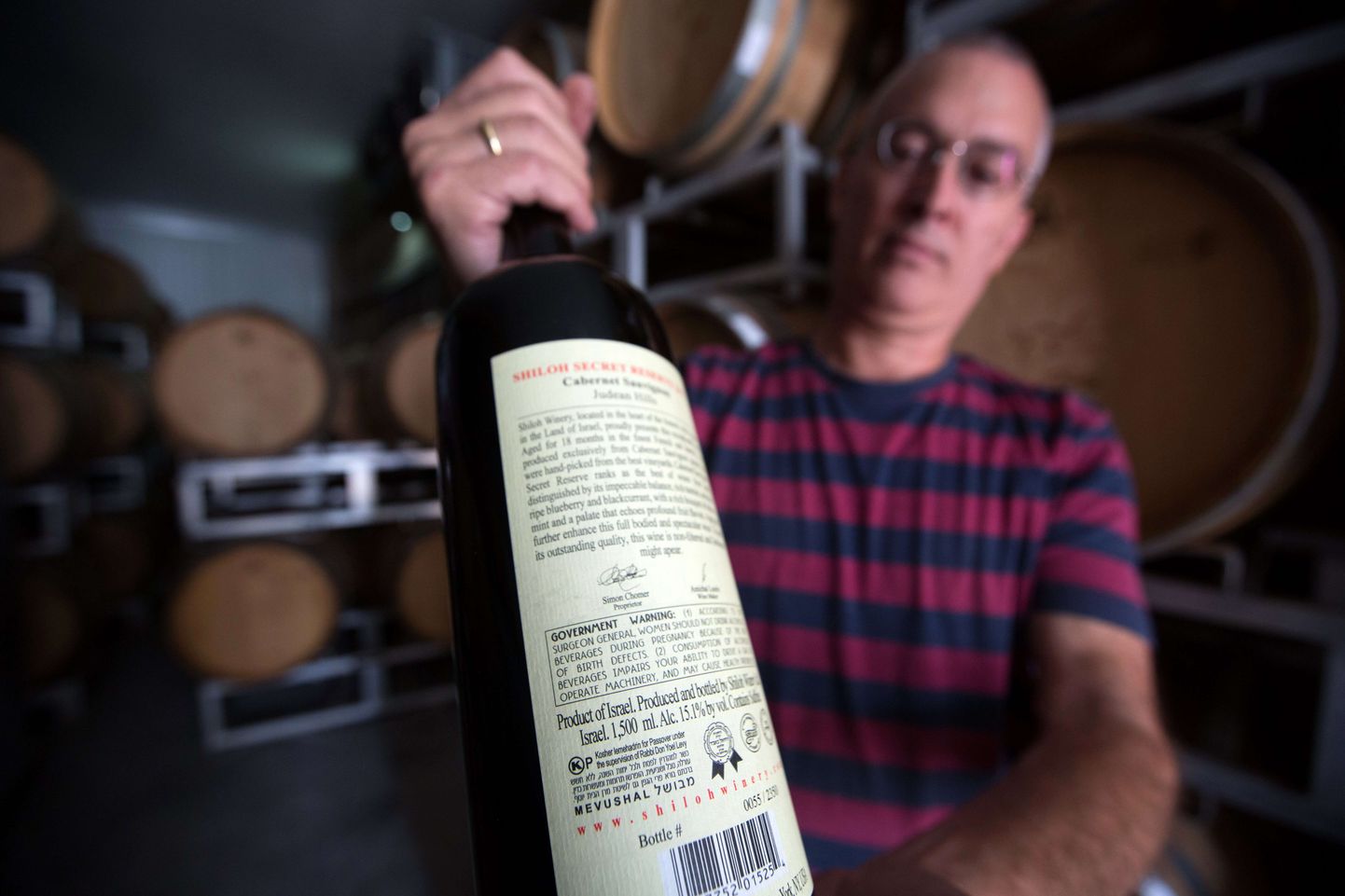 Läänekalda okupeeritud alade juudiasunduse veinitootja Amichai Luria näitab oma valdavalt ekspordiks mineva veinipudeli märgistust.