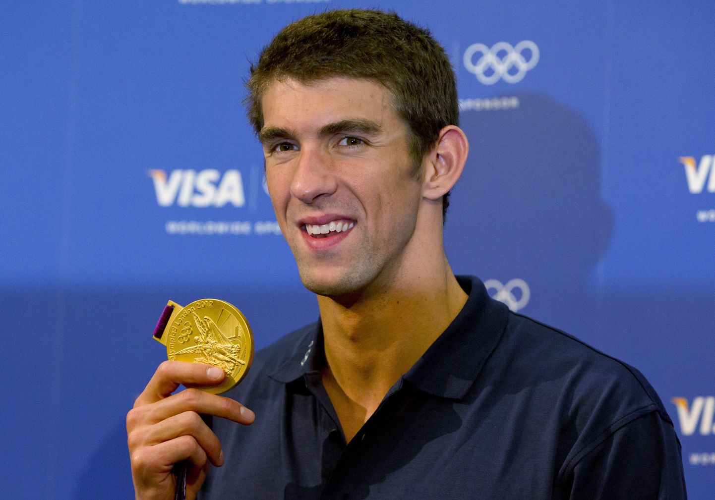 Michael Phelps Londoni OMilt võidetud kuldmedalit demonstreerimas.