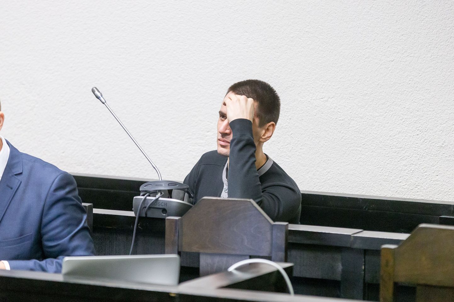 Арсений Яковлев в зале суда пытается спрятать лицо от фотографа.