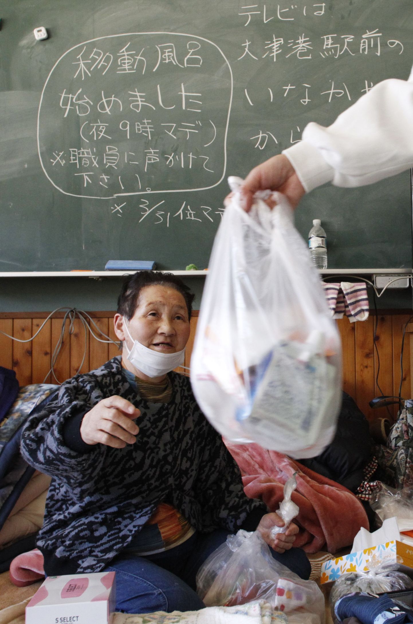 Meditsiinitöötaja ulatamas ravimeid eakale jaapanlannale, kes elab Otsu algkoolis asuvas evakuatsioonikeskuses