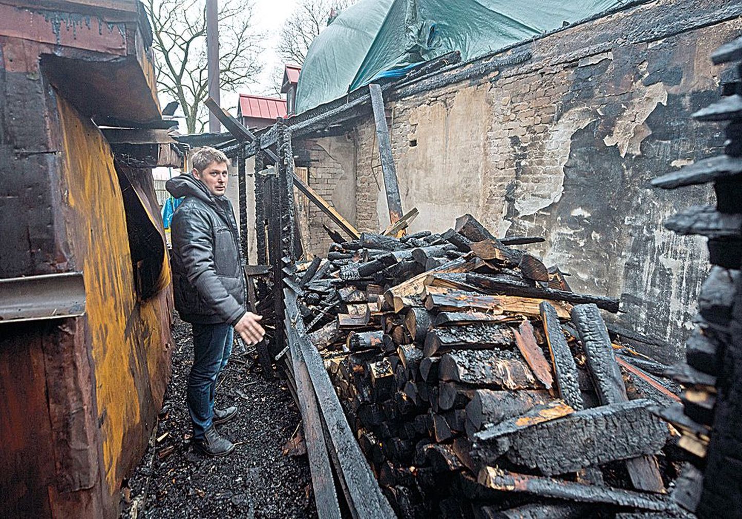 Владелец бара Андрей Кирилов показывает поленницу дров, с которой и начался пожар, влажные поленья сами не могли 
загореться, поэтому он предполагает, что это был поджог.