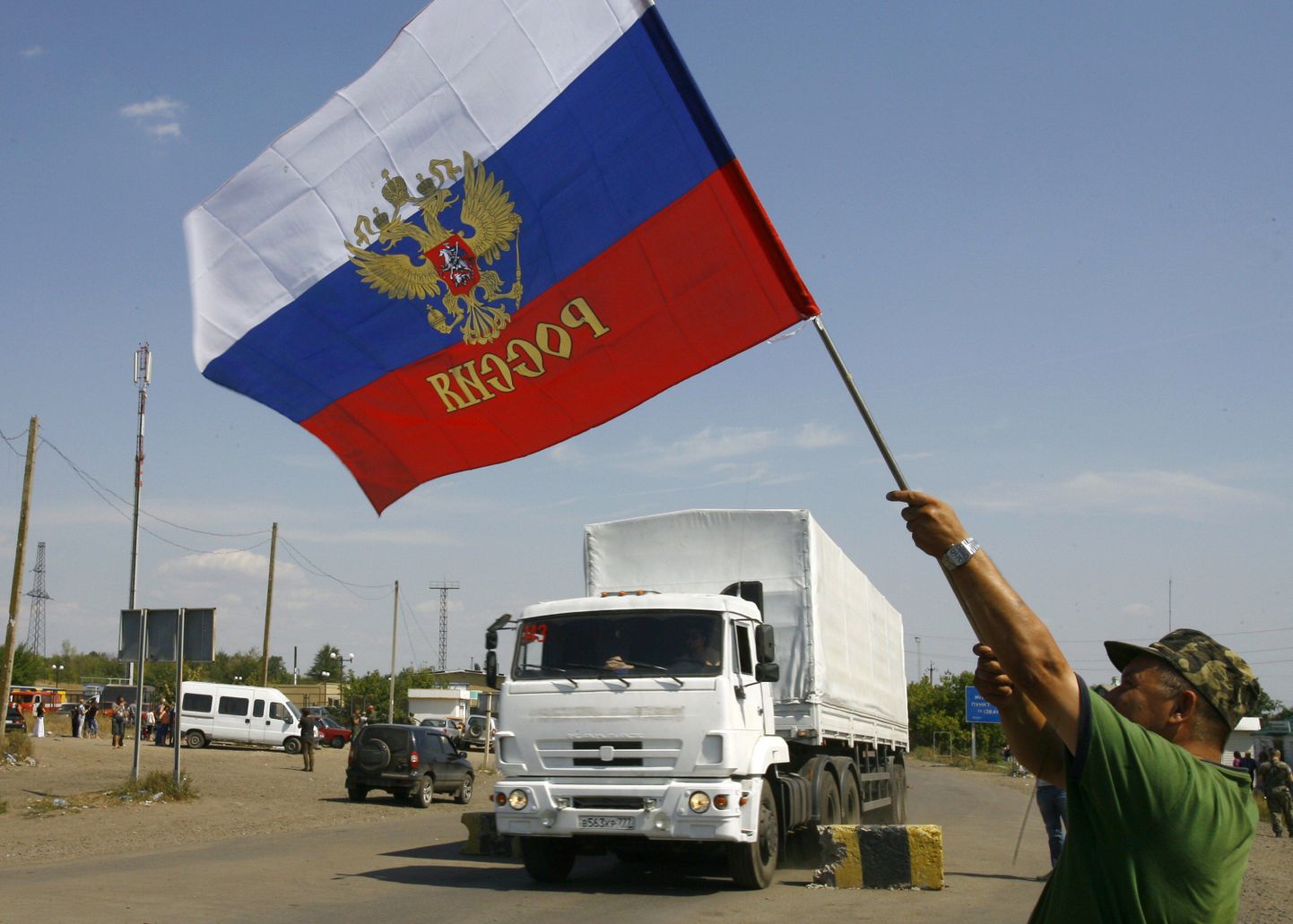 Местный житель приветствует российские грузовики из гуманитарного конвоя на украинской территории.