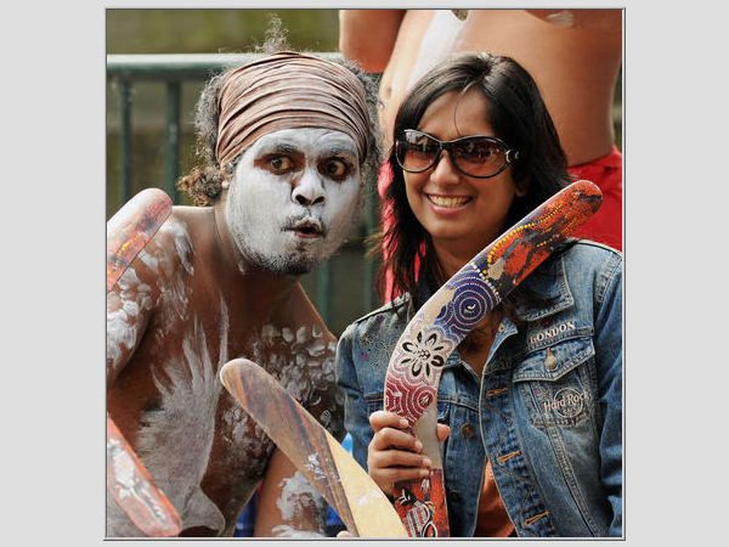 Turist (paremal) ja Austraalia aborigeen bumerangidega poseerimas.