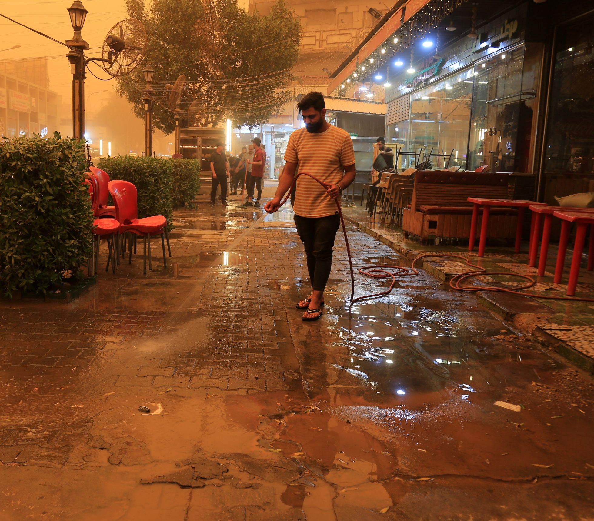 Bagdadi poepidaja koristab tänavat liivast, mille torm linna kandis.