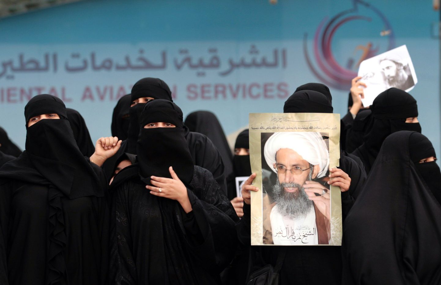 Saudi šiiidi naised hoiavad plakatit tapetud šiiavaimuki fotoga