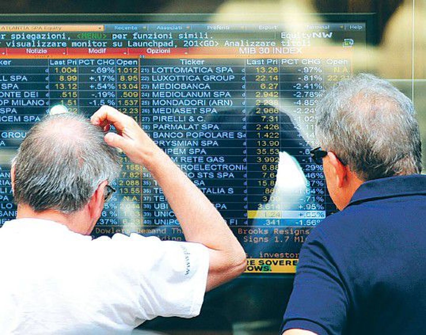 Люди изучают цены на акции на экране на здании Миланской биржи.