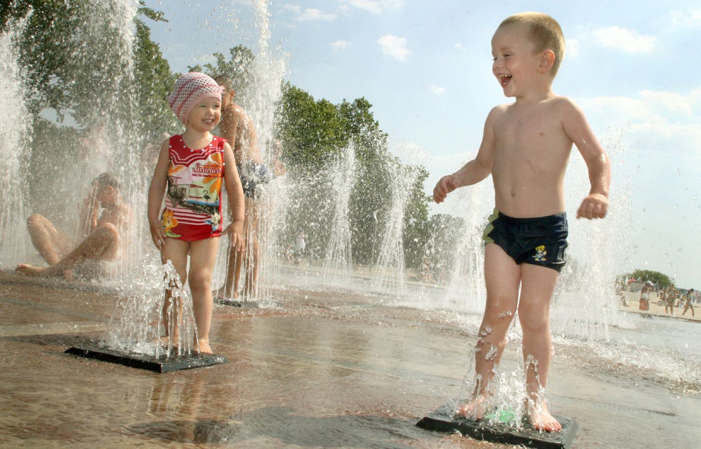 Дети спасаются от жары в фонтане.