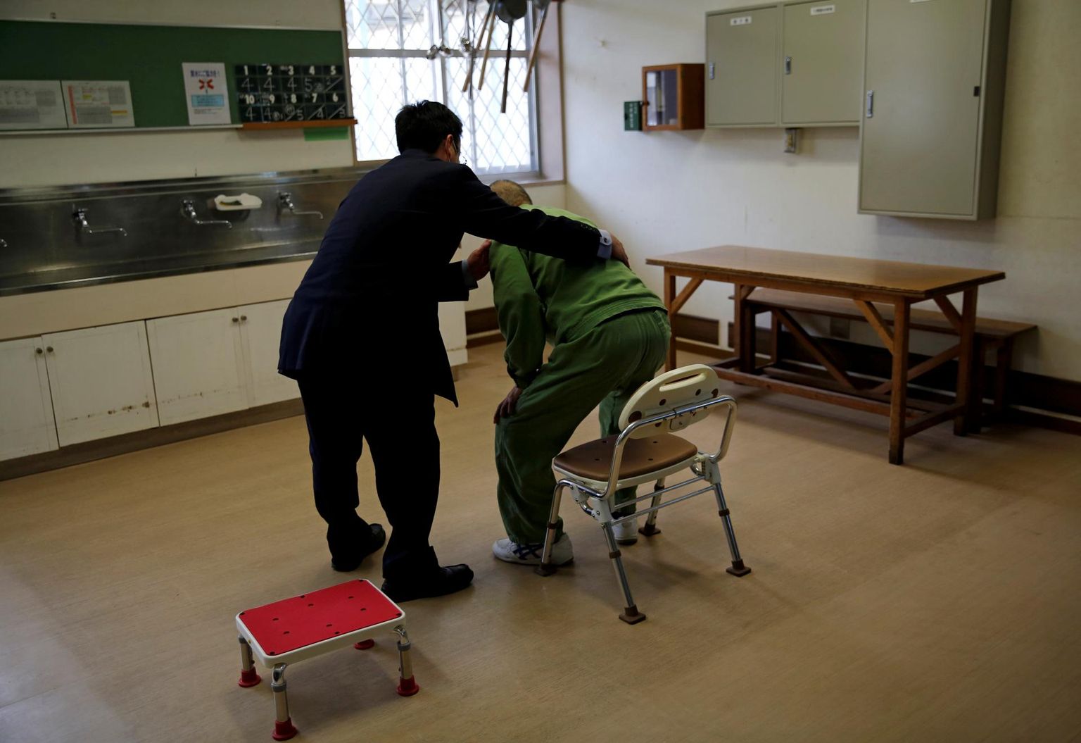 Tokushima vangla ametnik aitab eakal vangil liikuda.