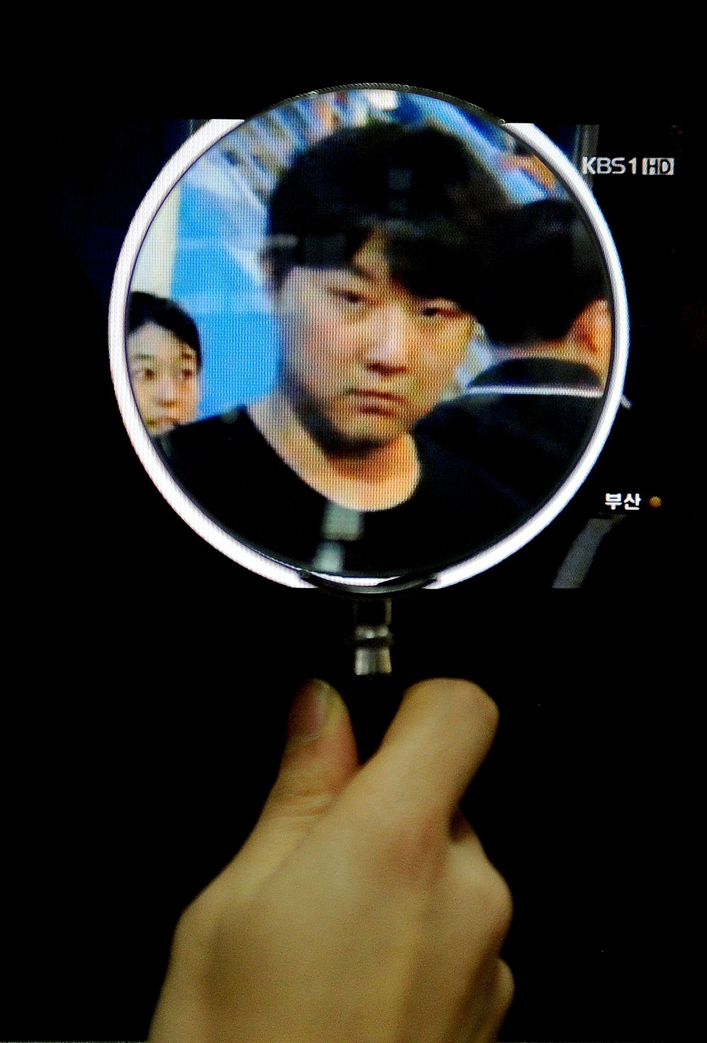 Lõuna-Korea teletöötaja vaatamas arvutiekraanilt suurendusklaasi abil Kim Jong-Cholist tehtud fotot