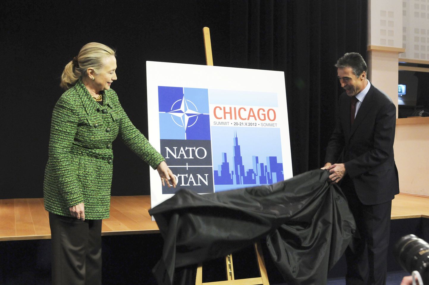 NATO peasekretär Anders Fogh Rasmussen ja USA välisminister Hillary Clinton võtmas katet Chicago tippkohtumise logolt.