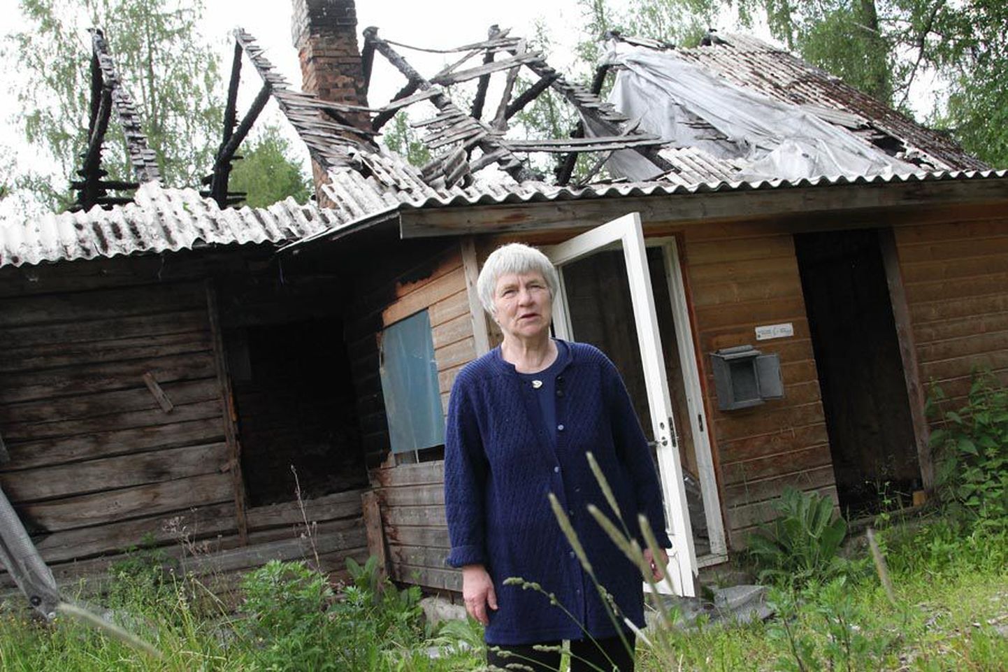 Tekstiilikunstnik Anu Raud vaestemaja ees, mis kahe aasta taguses tulekahjus tugevasti kannatada sai.
