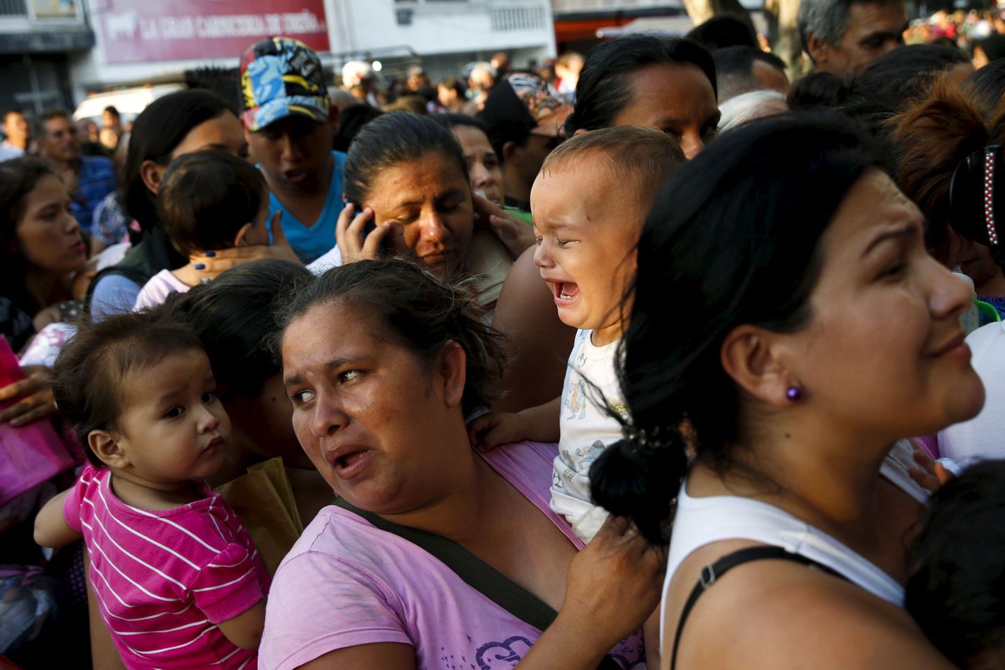 Lastega naised Venezuela supermarketi ukse taga piimajärjekorras.