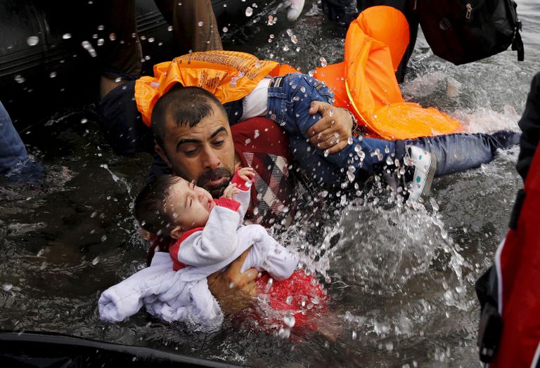 Mees lapsega üritab viletsast veesõidukist Lesbose saare kaldale pääseda.