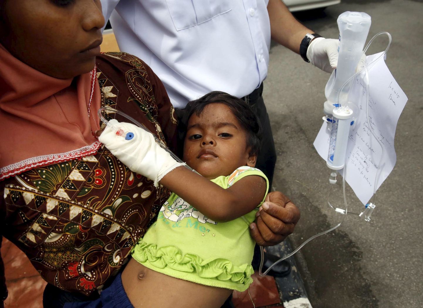 Langkawi saarele maabunud migrant, kelle last Malaisia meditsiinitöötaja parajasti turgutab.