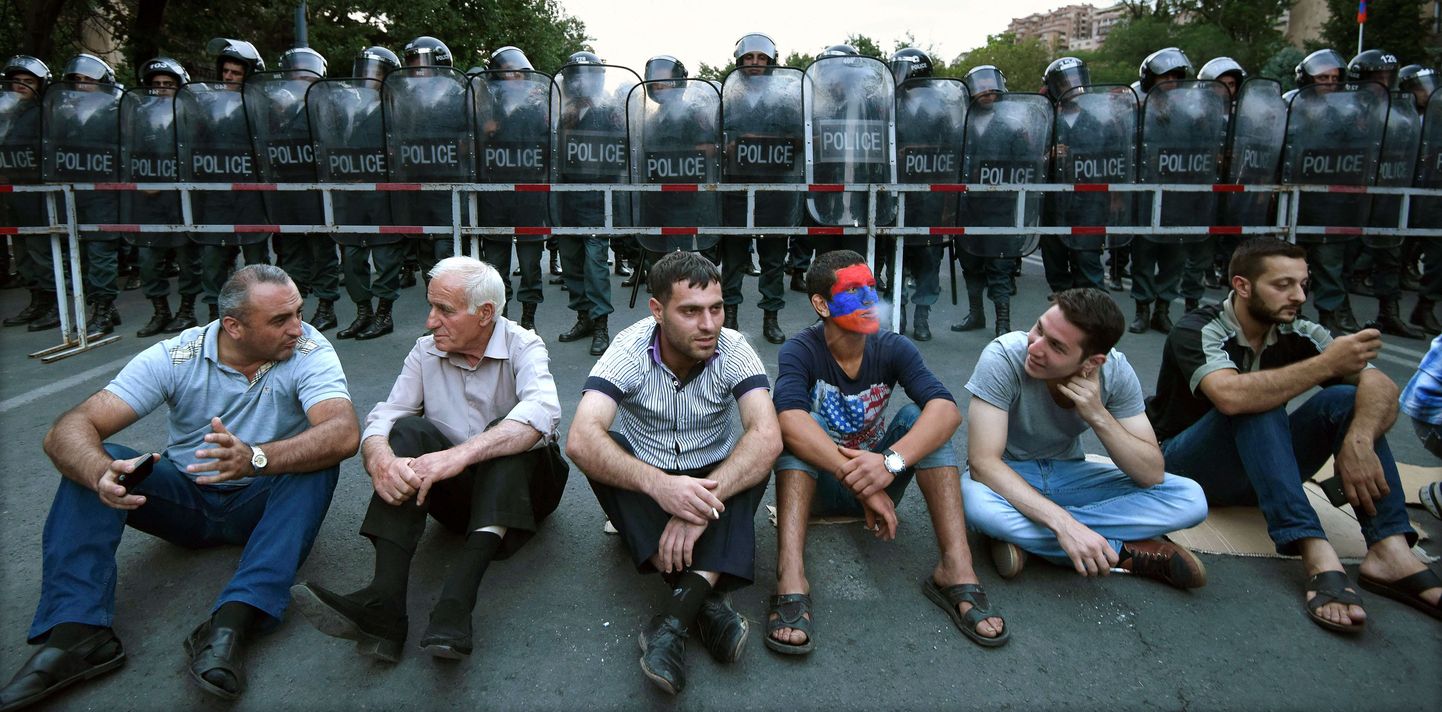 Armeenia märulipolitseinikud seismas istuvate meeleavaldajate taga
