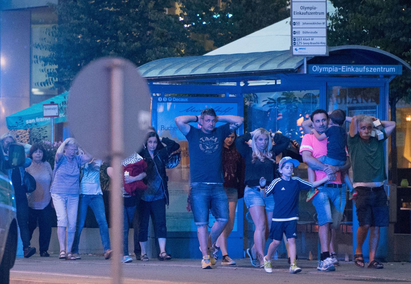 Посетители покидают торговый центр в Мюнхене с поднятыми руками, поселе произошедшей там стрельбы.