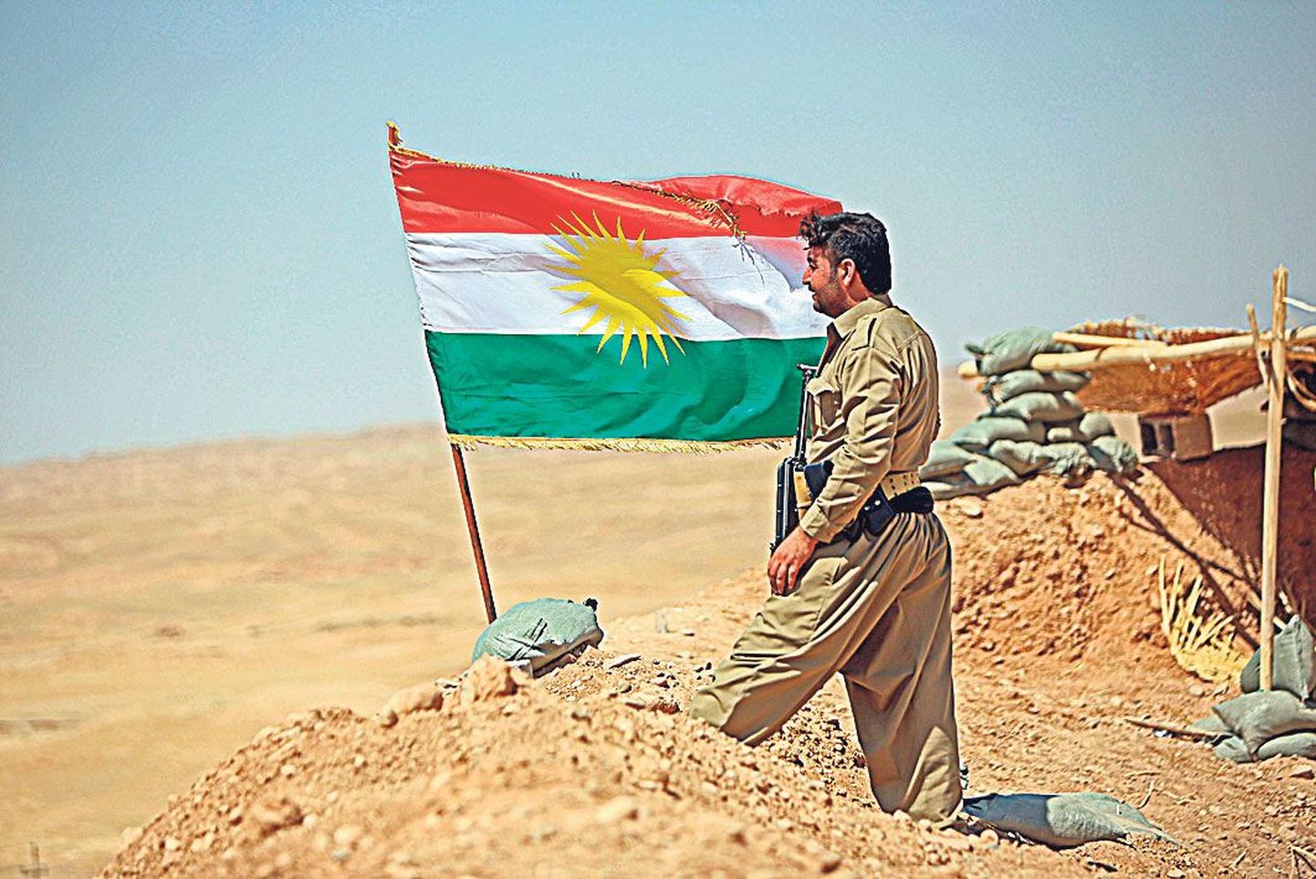 Pešmerga võitleja Kurdistani lipu taustal.