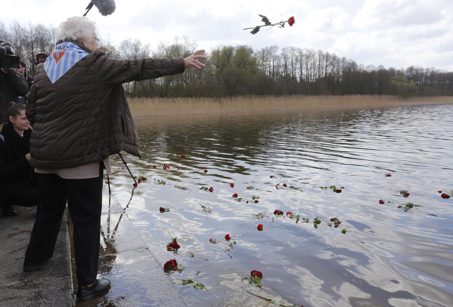 Natsi-Saksamaa Ravensbrücki koonduslaagrist eluga pääsenud naine heidab vette roose seal hukkunute mälestuseks.