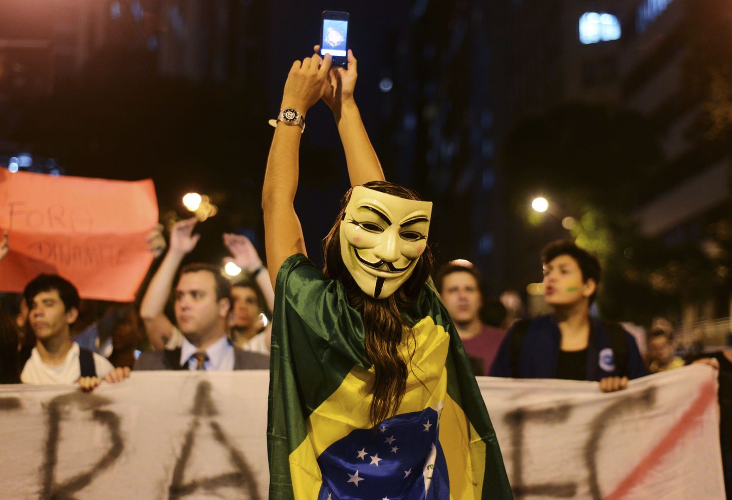 Guy Fawkesi maski ja Brasiilia lippu kandev meeleavaldaja.