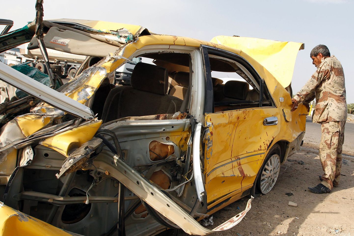 Iraagi sõdur uurib autopommi plahvatuses hävinud sõidukit.
