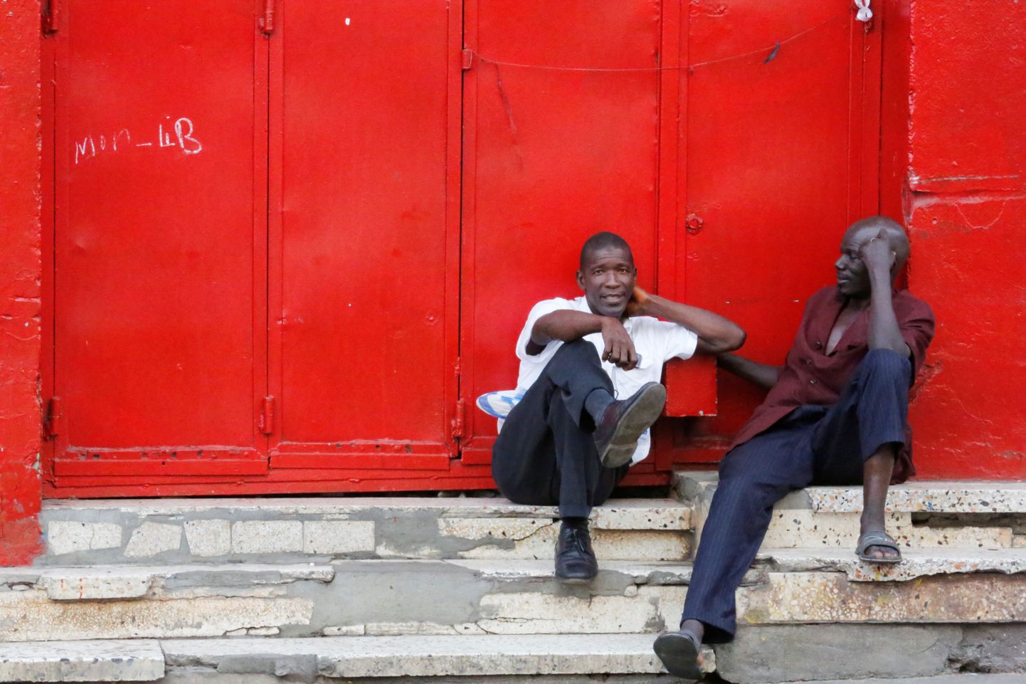 Mehed istumas Libeeria pealinnas Monrovias asuva suletud kaupluse ees.