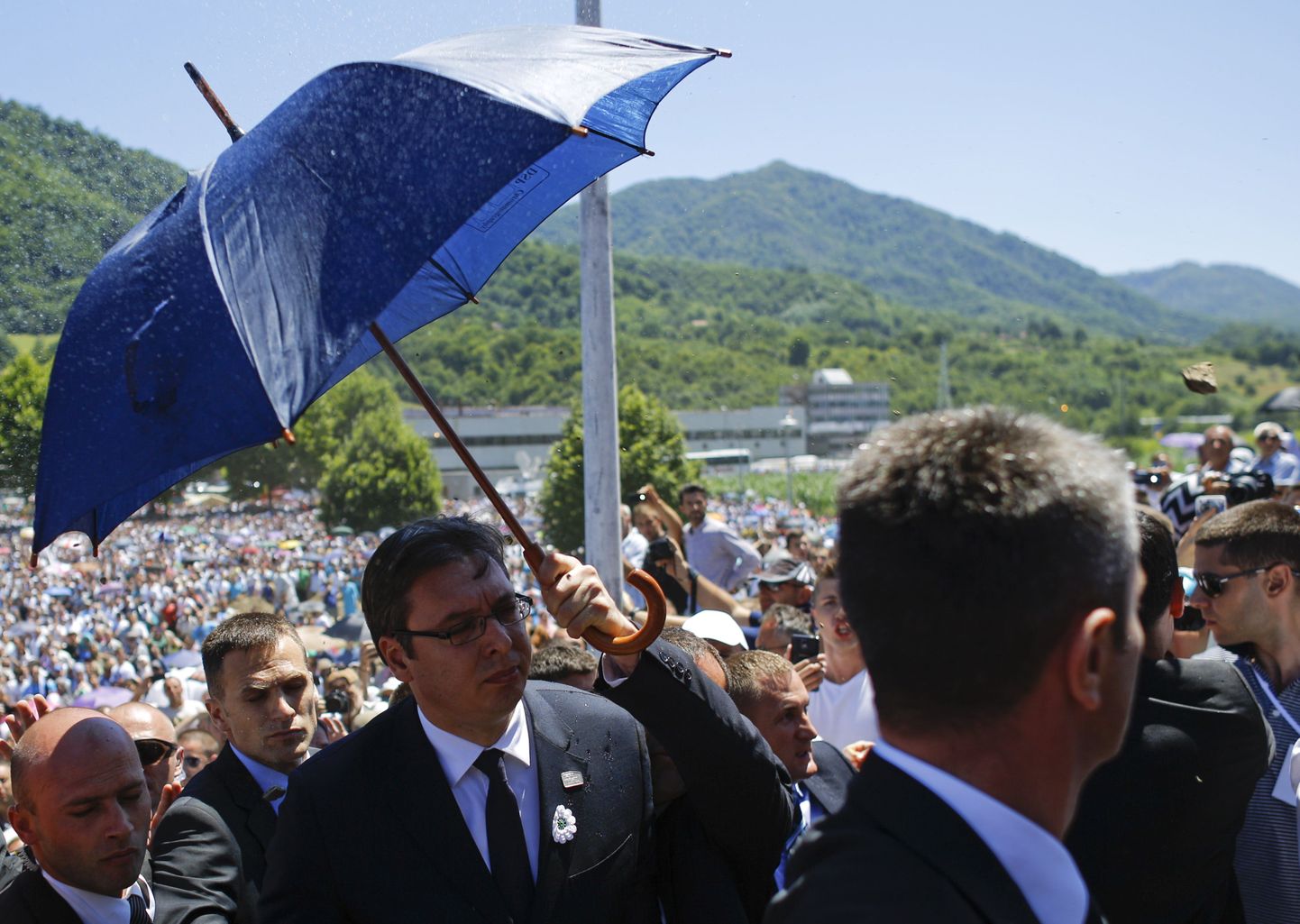 Ihukaitsjad blokeerimas Serbia peaministri Aleksandar Vučići poole visatud kivi vihmavarjuga.