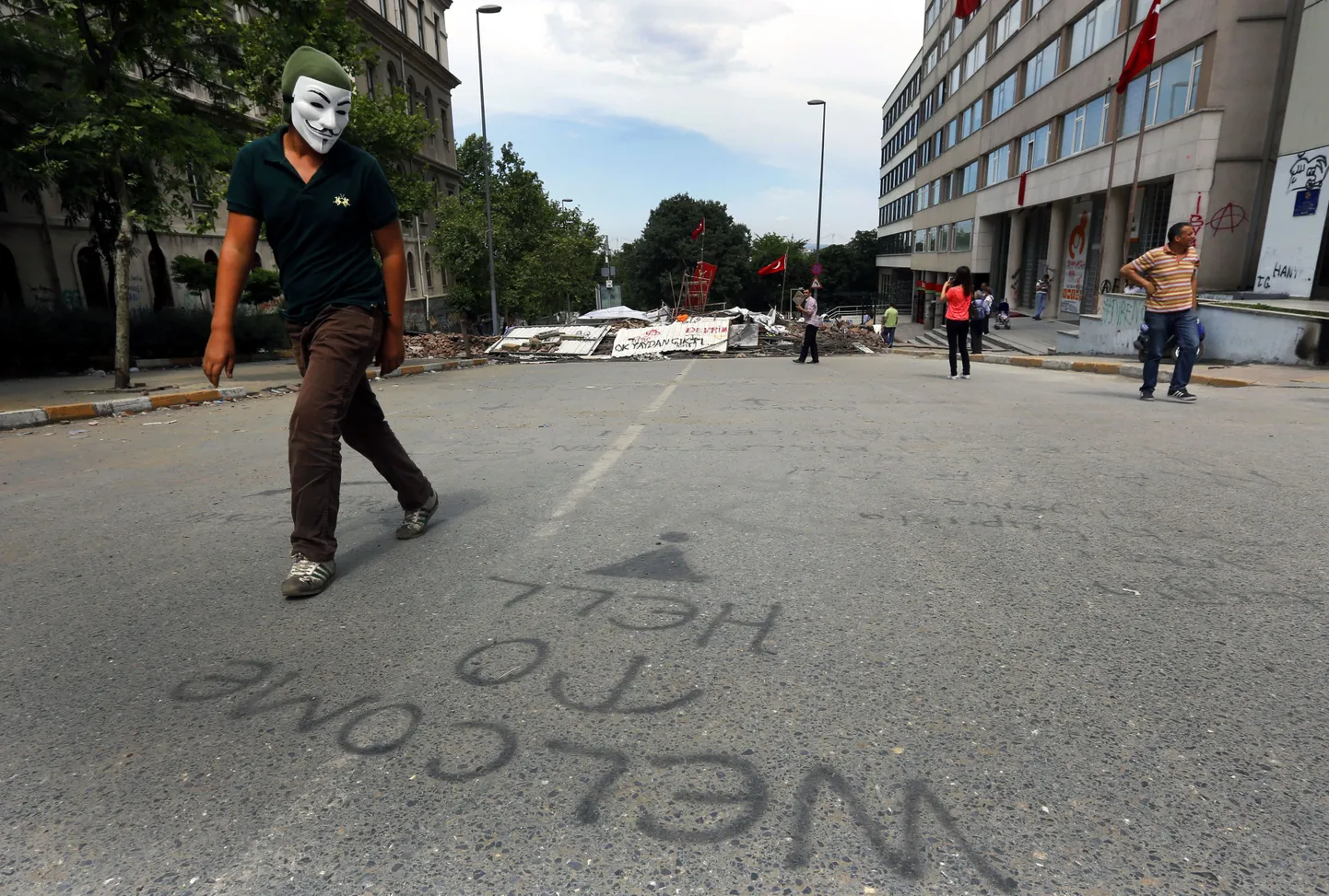 Guy Fawkesi maski kandev valitsusvastane kõnnib Istanbuli tänaval mööda gräfitist "Tere tulemast põrgusse".