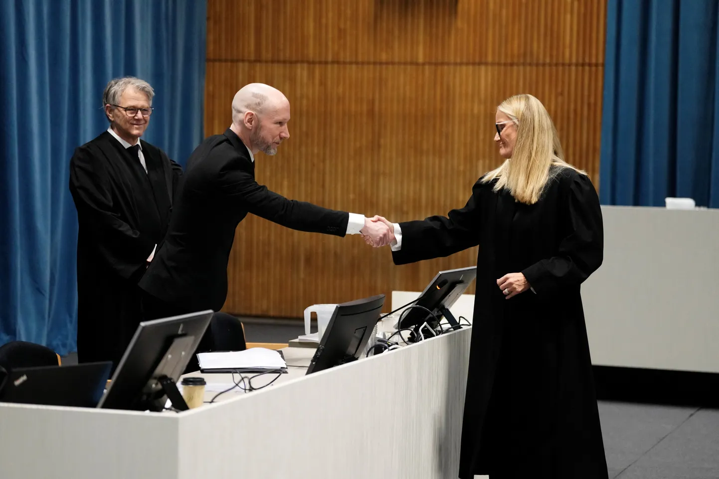Norra massimõrvar Anders Behring Breivik, keda tuntakse ka kui Fjotolf Hansen, surumas 19. novembril 2024 Ringerike, Askeri ja Baerumi ringkonnakohtus kätt prokuröri Hulda Karlsdottiriga, taga seisab Breiviki advokaat  Øystein Storrvik.