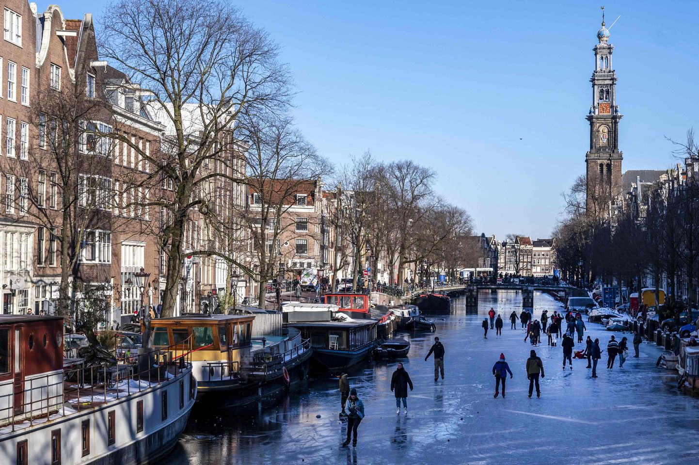Skaters gather on ice on the canals in Prinsengracht, Amsterdam on February 13, 2021, as municipal authorities called on residents to go skating in their own neighbourhoods to prevent the build up of crowds and thus attempt to halt the spread of the coronavirus (Covid-19). (Photo by Evert Elzinga / ANP / AFP) / Netherlands OUT
