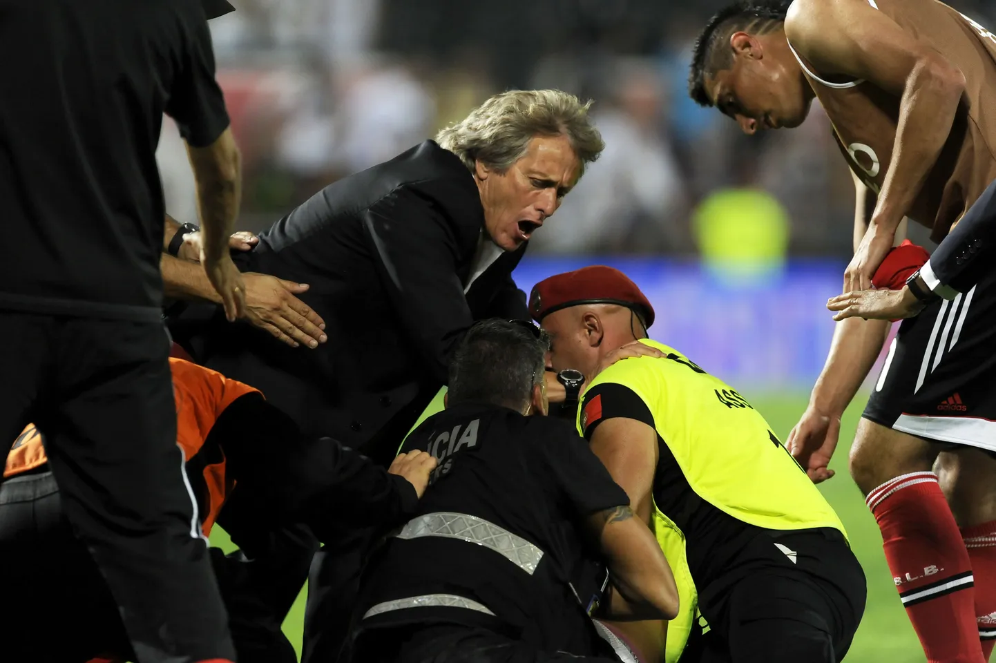 Benfica peatreener Jorge Jesus (keskel) püüab fänni politseinike haardest vabastada.