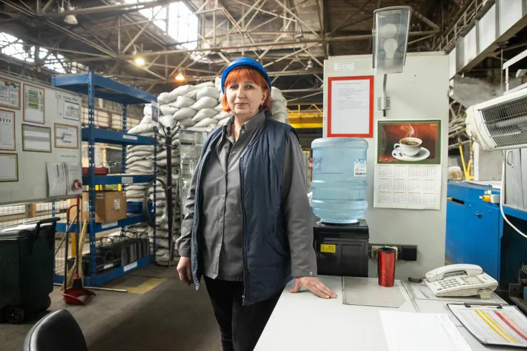 Torude kuumtöötluse tsehhi vahetuse ülem Oksana Boiko oma töölaua taga. Taga paistab metallkonstruktsiooniga varjend, mis on vooderdatud liivakottidega. Sellised varjendid on tehases iga mõnekümne meetri järel.
