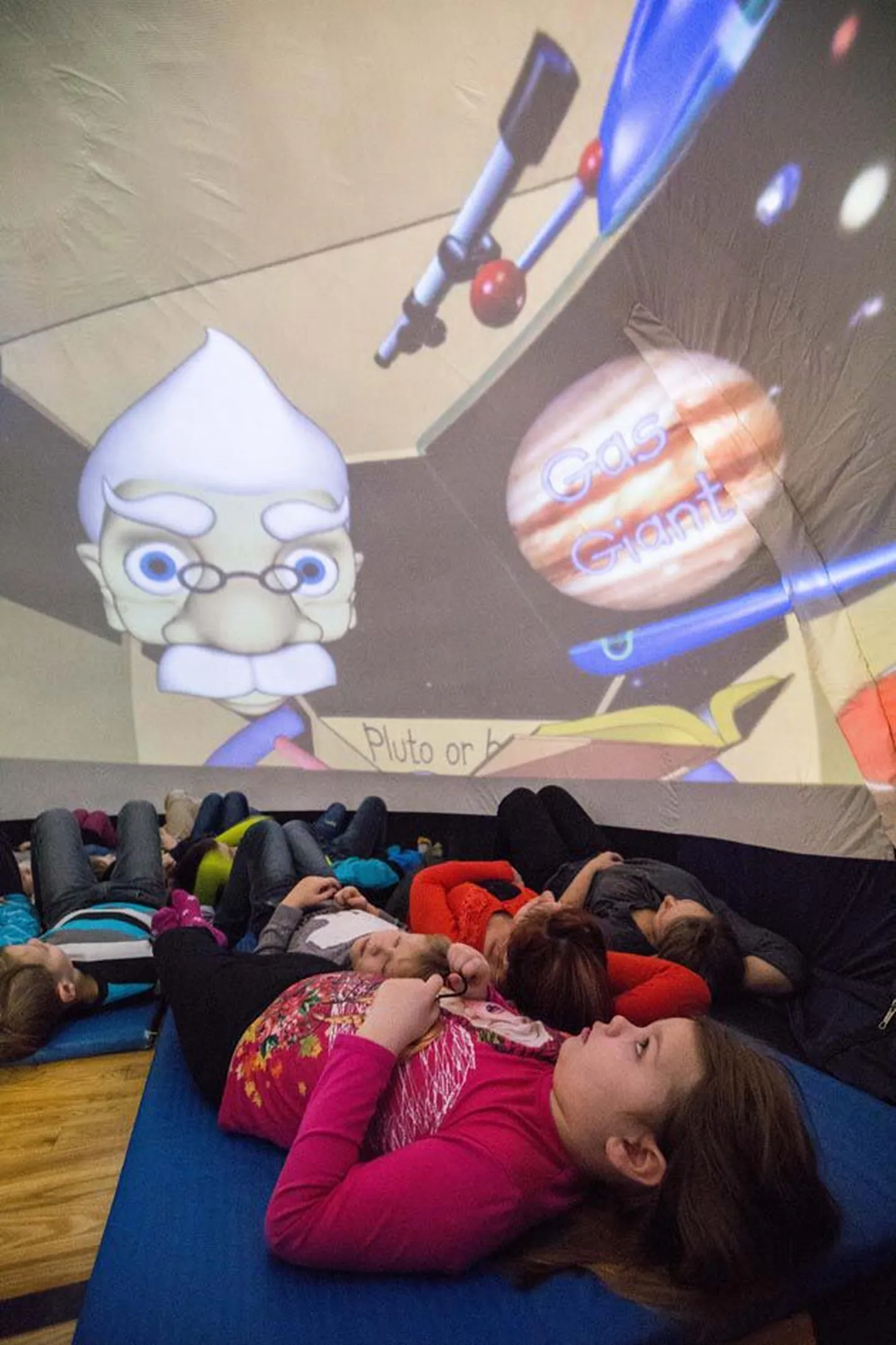 Maria Lotta Saar (esiplaanil) vaatab koos koolikaaslastega pikutades kupli laest ja külgedelt põnevat animatsiooni laste rännakust mööda planeete.