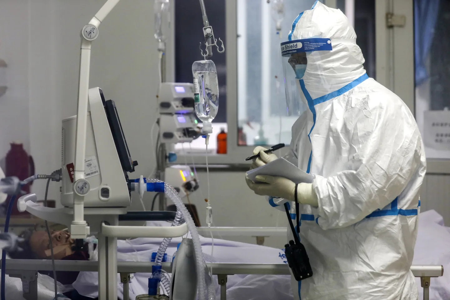 In this Sunday, Feb. 16, 2020, photo, a medical worker records down a patient's condition at Jinyintan Hospital designated for new coronavirus infected patients, in Wuhan in central China's Hubei province.
