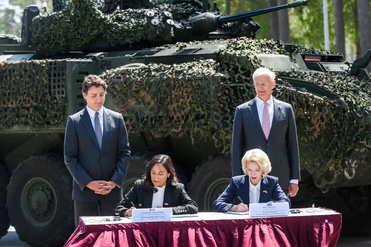 Kanada kaitseminister Anita Anand (vasakult teine) ja Läti kaitseminister Ināra Mūrniece (paremalt teine) allkirjastavad Kanada juhitud NATO eelpaigutatud väegruppi puudutava kokkuleppe. Nende taga seisavad Kanada peaminister Justin Trudeau (vasakul) ja Läti peaminister Krišjānis Kariņš (paremal). Pilt on tehtud 10. juulil 2023.