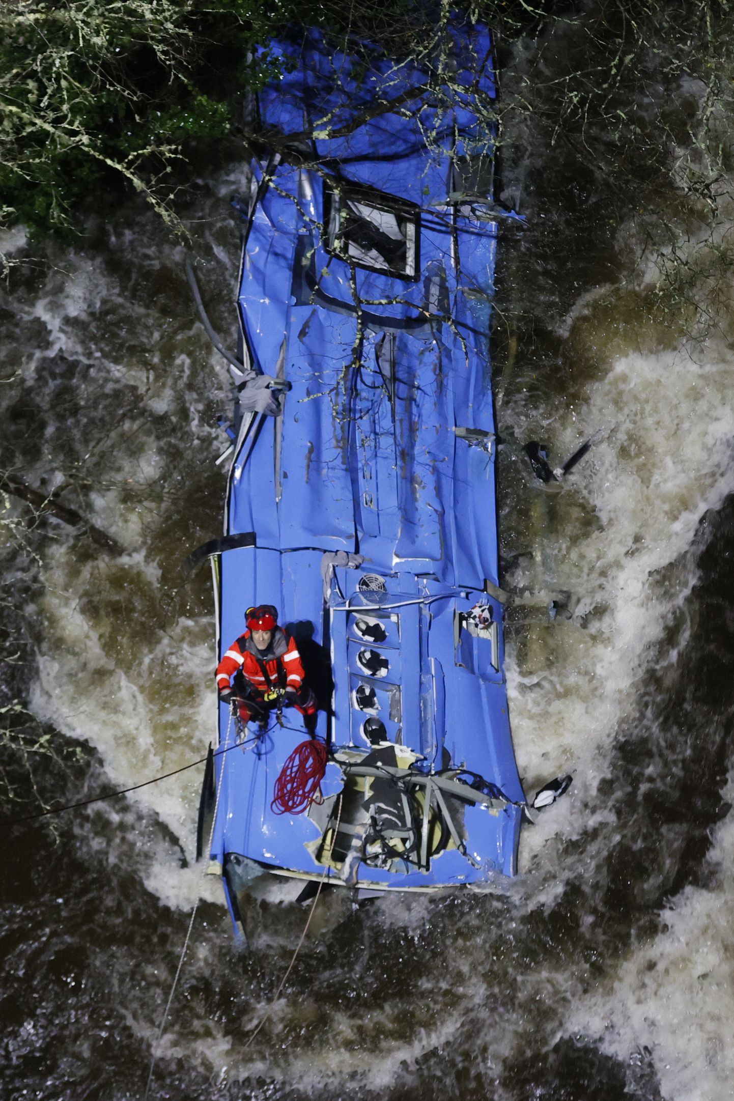 Испанский спасатель поднимает автобус, упавший в реку Лерезе. Автобус упал в реку при пересечении моста. Два человека погибли и трое пропали без вести.