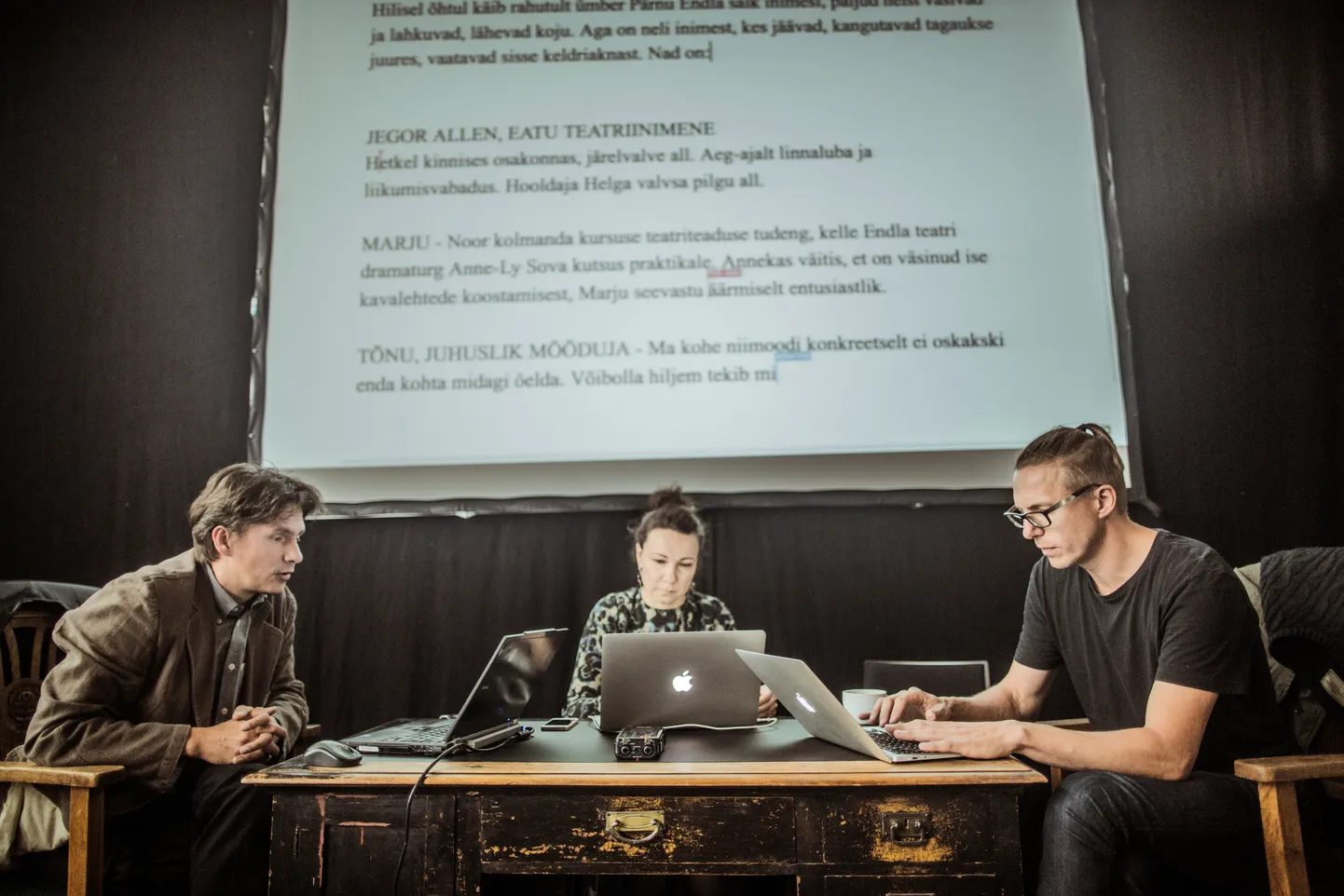 Näitekirjanikud Draama festivalil lühinäidendit kirjutamas, laua taga on Mart Aas, Piret Jaaks ja Urmas Vadi.