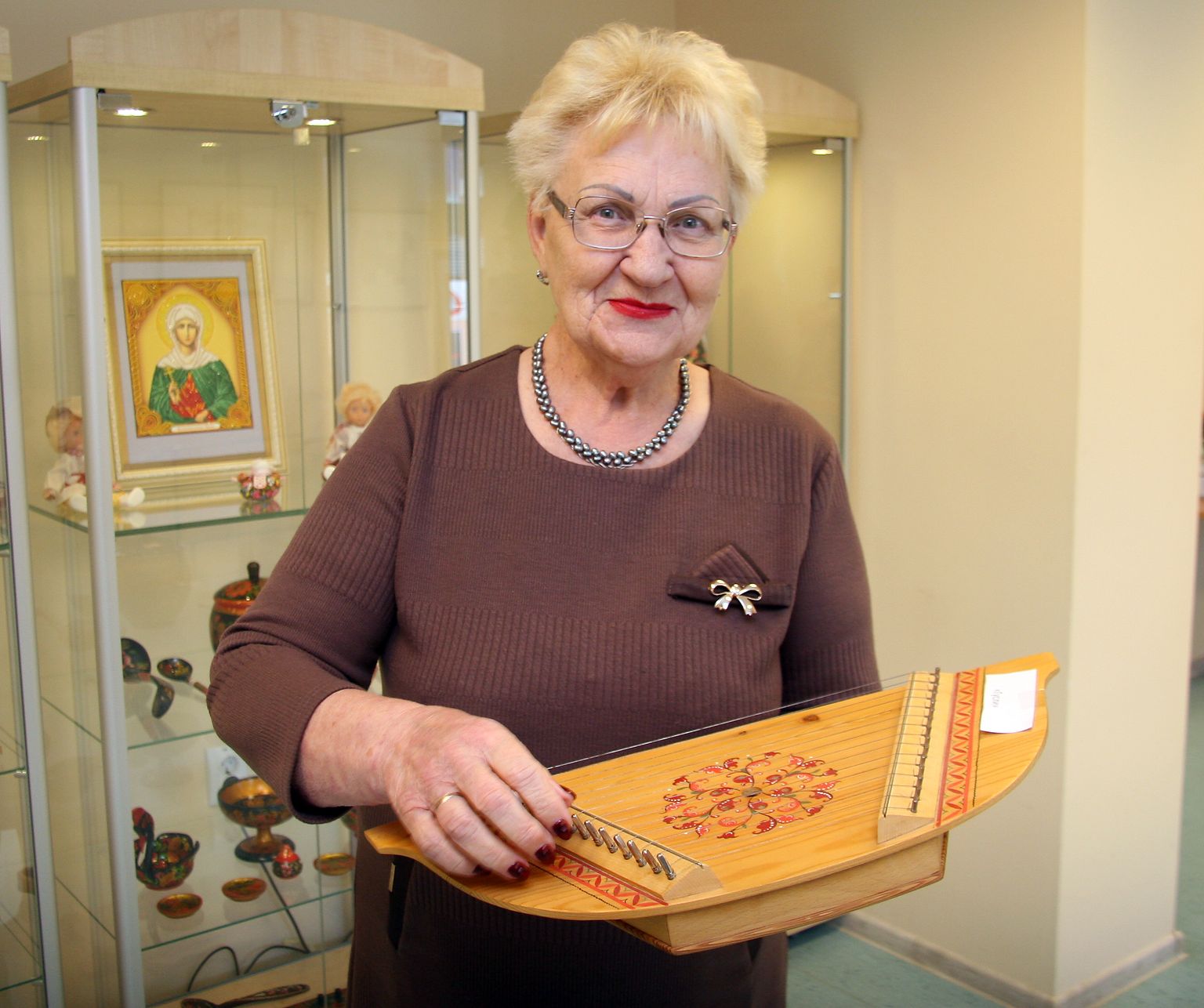 Роза Иванова демонстрирует русский народный инструмент - гусли, они были изготовлены специально в подарок кохтла-ярвескому музею.