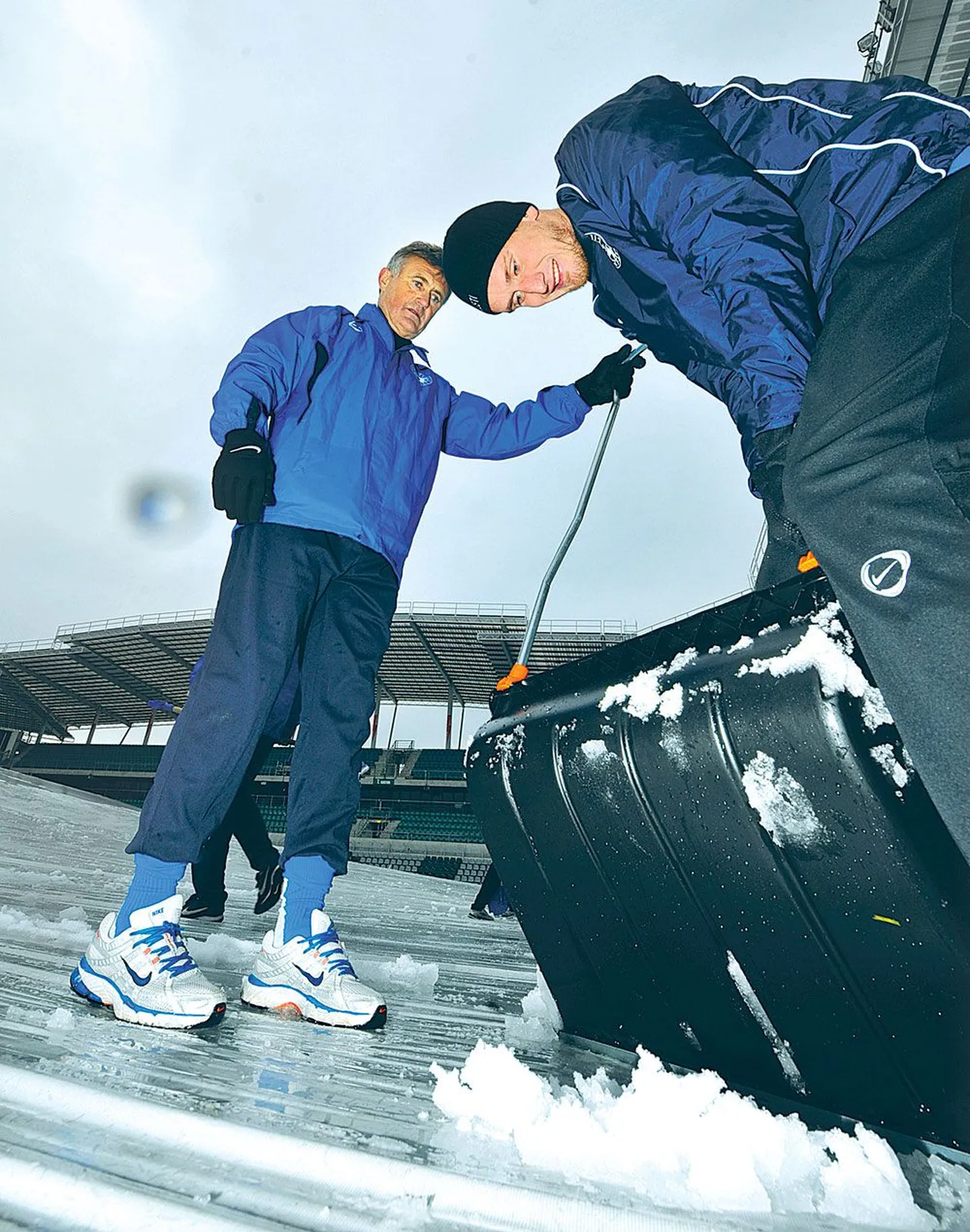 Fredrikstadiga Norra esiliigasse kukkunud Eesti jalgpallikoondislane Raio Piiroja (paremal) ja peatreener Tarmo Rüütli aitasid eile koos kaaslastega Lilleküla staadionit lumest puhastada.