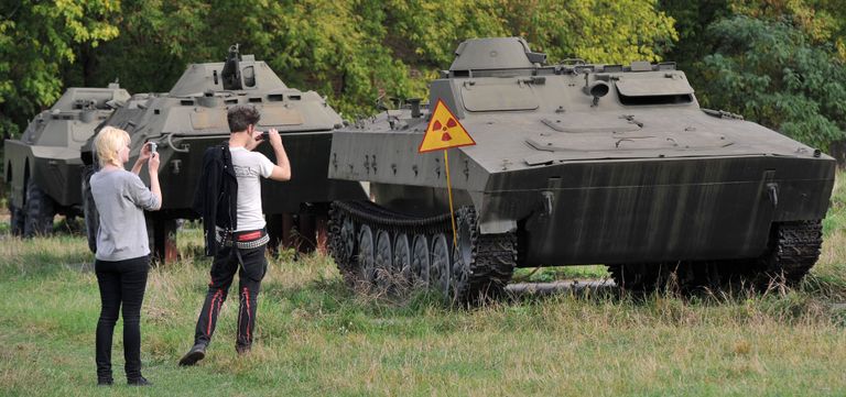 Rootsi turisitid tegemas fotot mahajäetud sõjaväetehnikast Tšornobõlist.