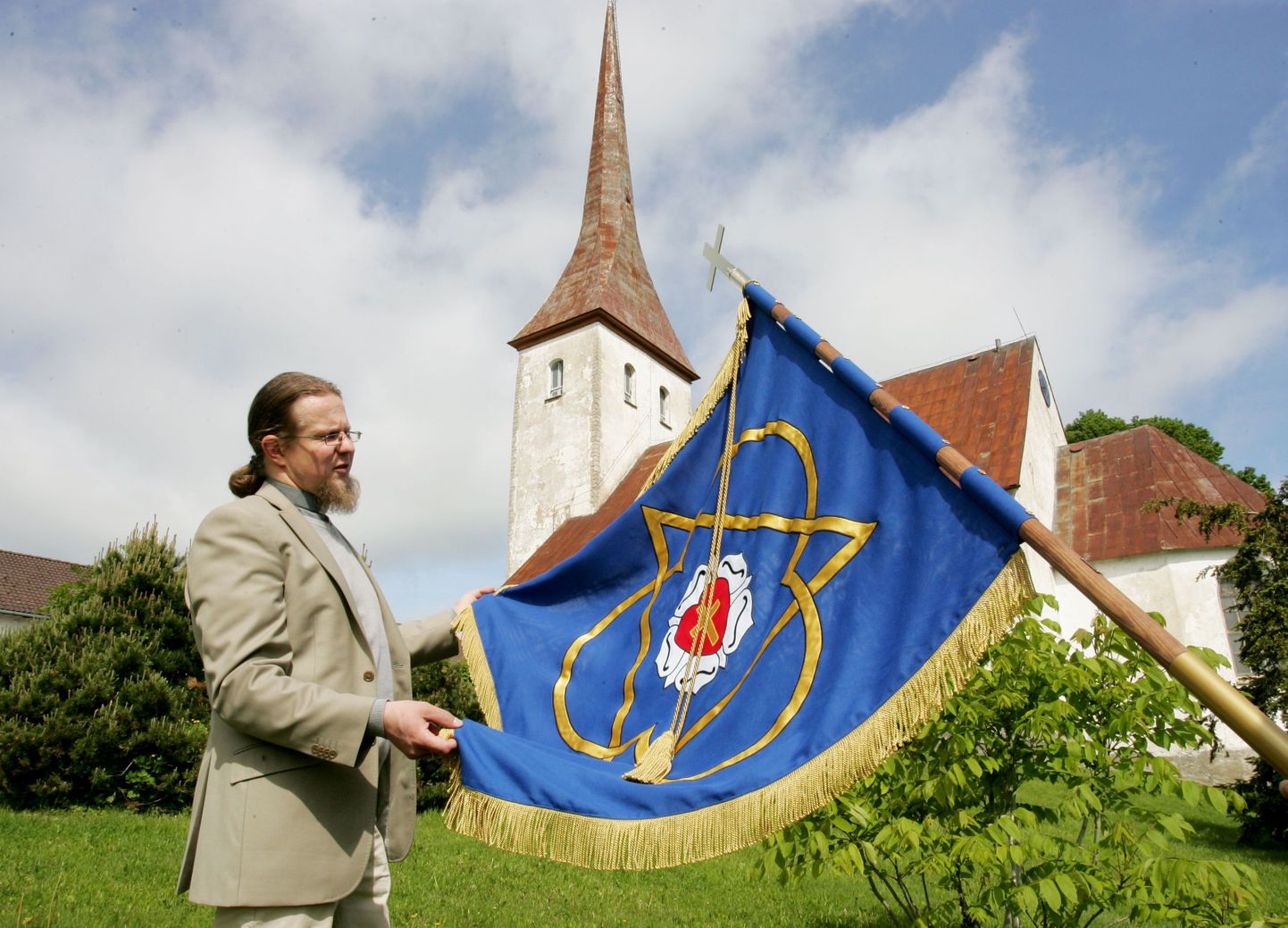 EELK Rakvere Kolmainu koguduse õpetaja Tauno Toompuu näitab koguduse uut lippu.