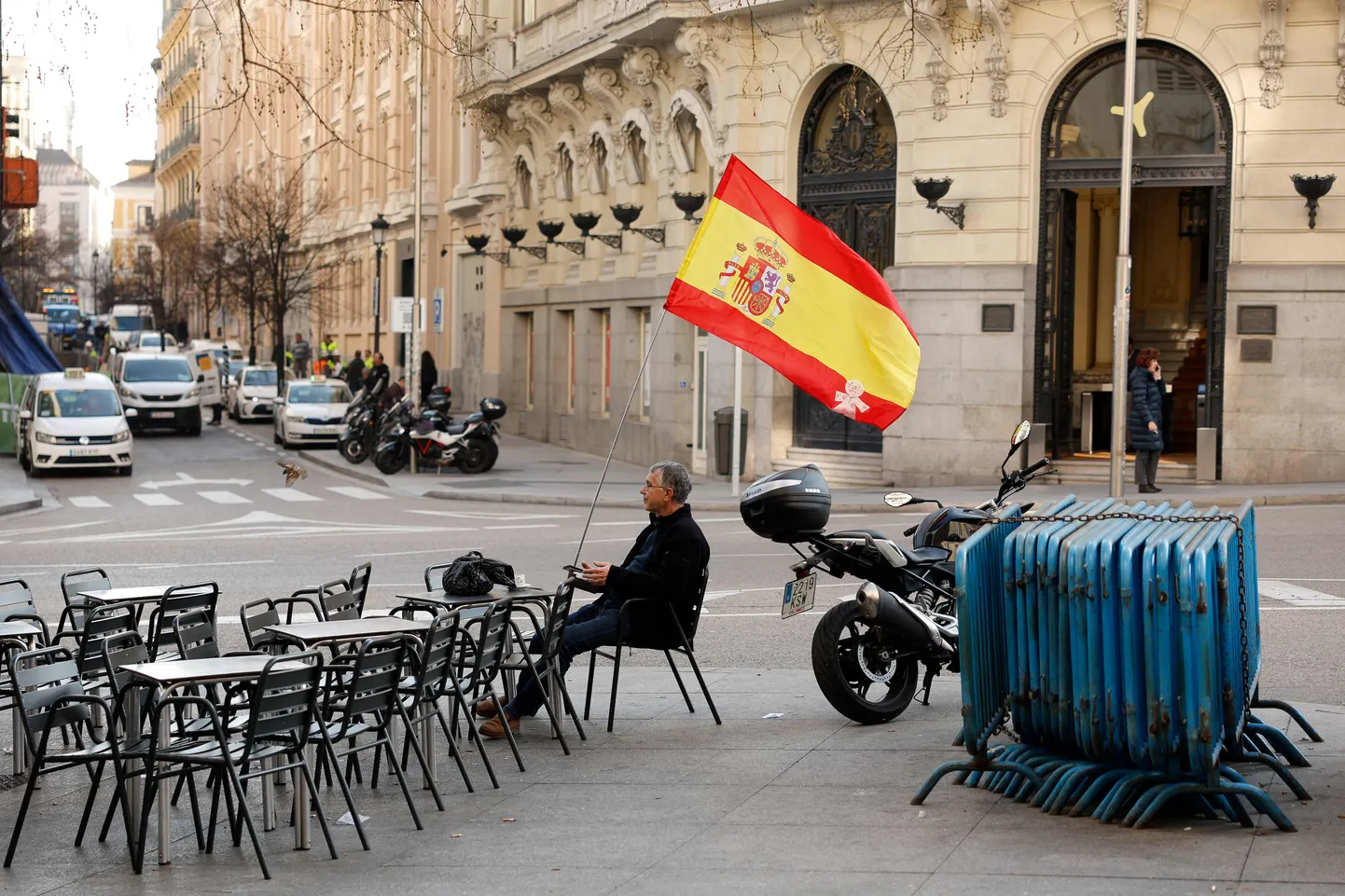 Hispaania lipuga mees üksinda väliterrassil parlamendihoone ees.