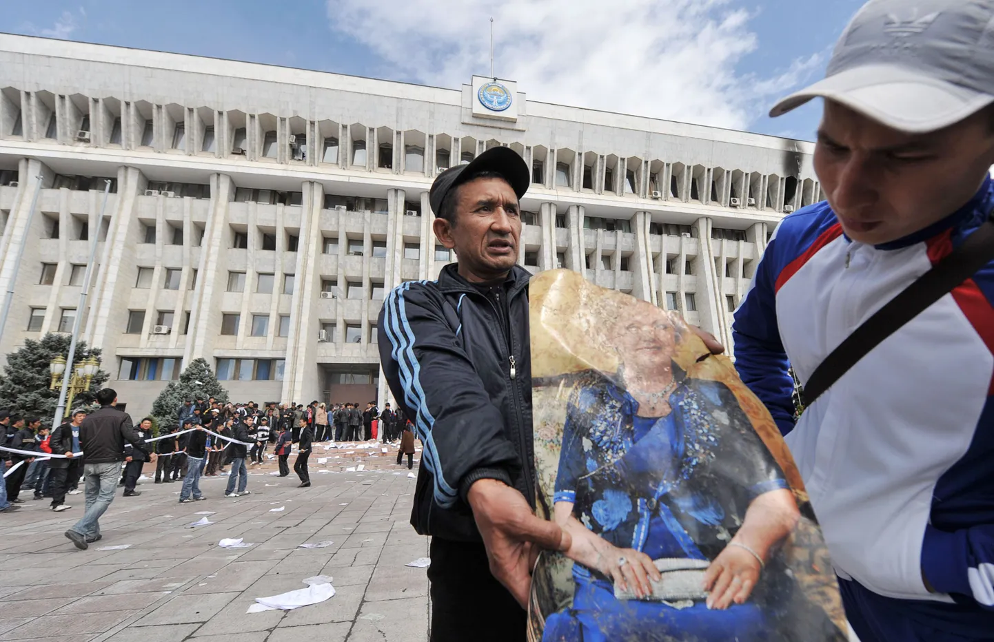 Kaks meest hoiavad käes Kõrgõzstani senise esimese leedi portreed. Taga paistab valitsushoone Biškekis.