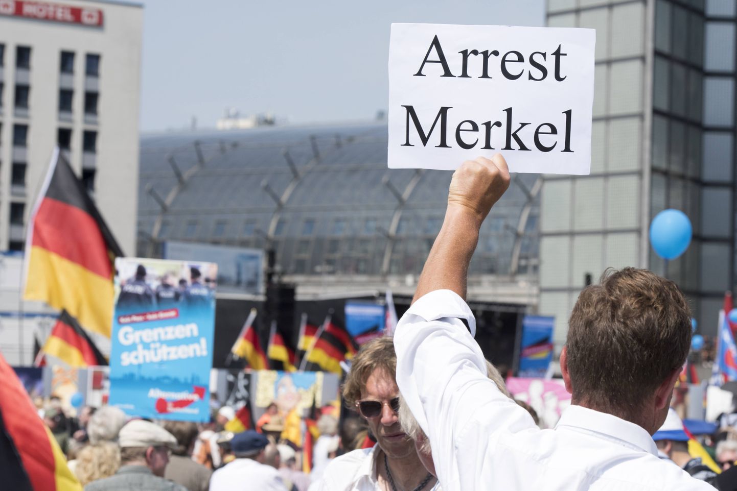 AfD toetaja hoidmas plakatit, millega nõuab Angela Merkeli arreteerimist.