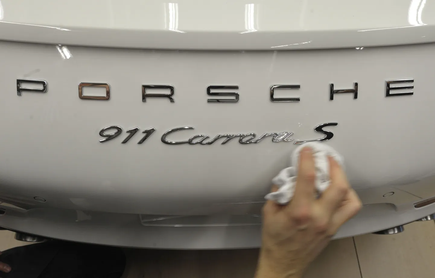 Porsche töötaja Stuttgarti tehases Porsche 911 sportautot puhastamas.