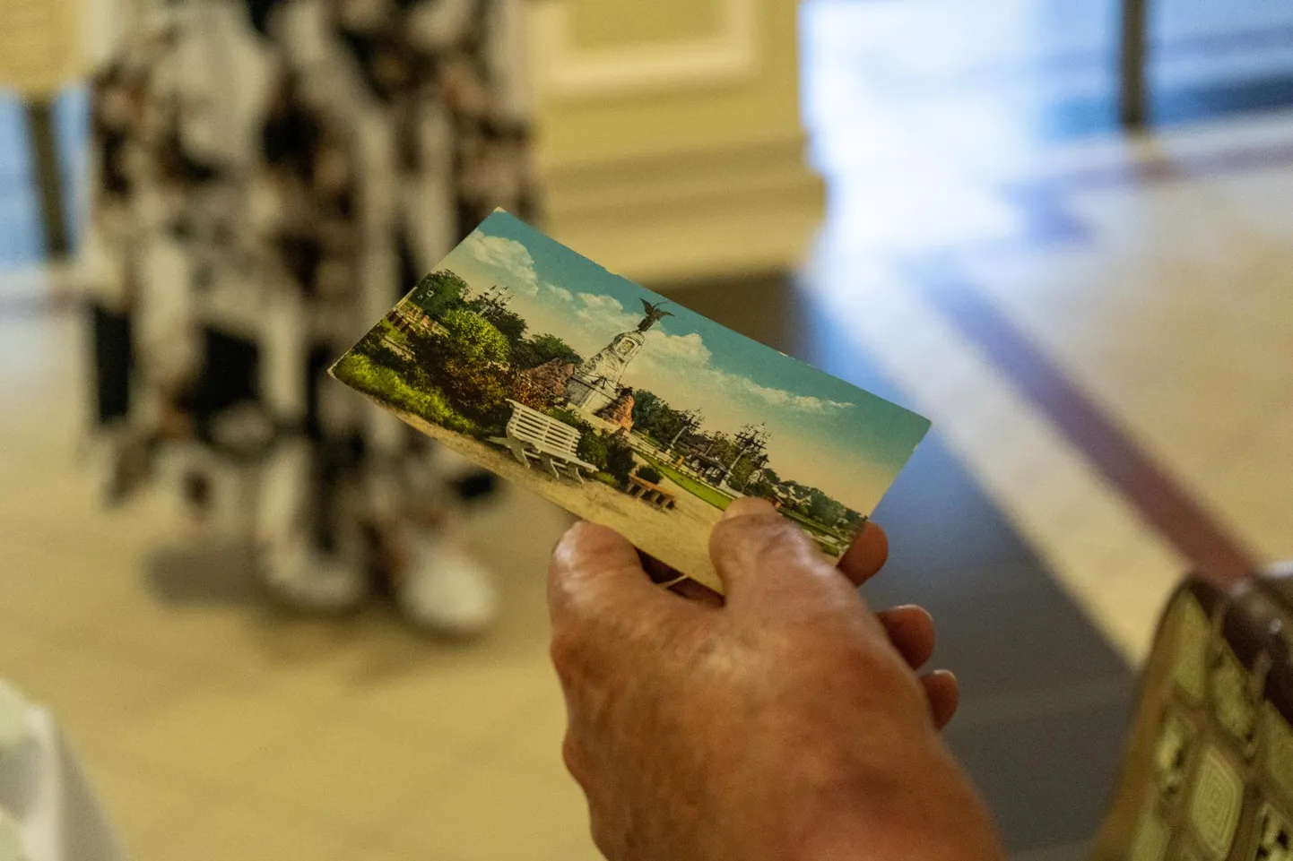 Fotograaf hoiab käes Tallinna vaatega postkaarti. Viljandi postkaartide suurendused on Sakala keskuses näitusel.