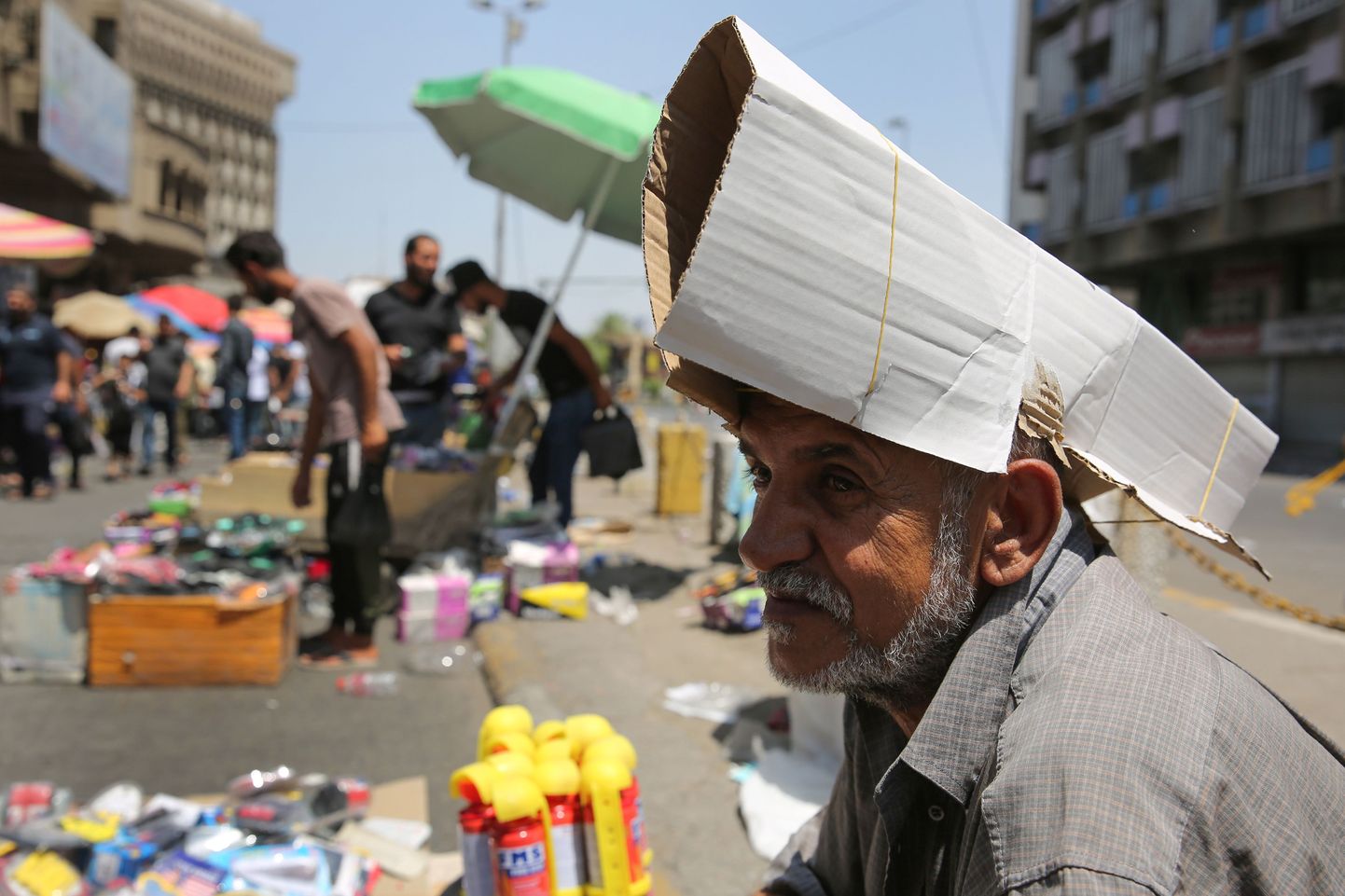 Bagdadi tänakaupmees kaitseb oma pead lõõskava päikese eest papitükiga.