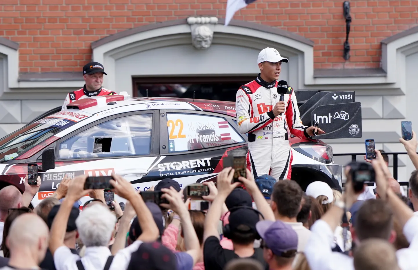 Stūrmanis Renārs Francis (no kreisās) un rallija pilots Mārtiņš Sesks piedalās FIA pasaules rallija čempionāta Latvijas posma "Tet Rally Latvia" atklāšanas ceremonijā Rātslaukumā.