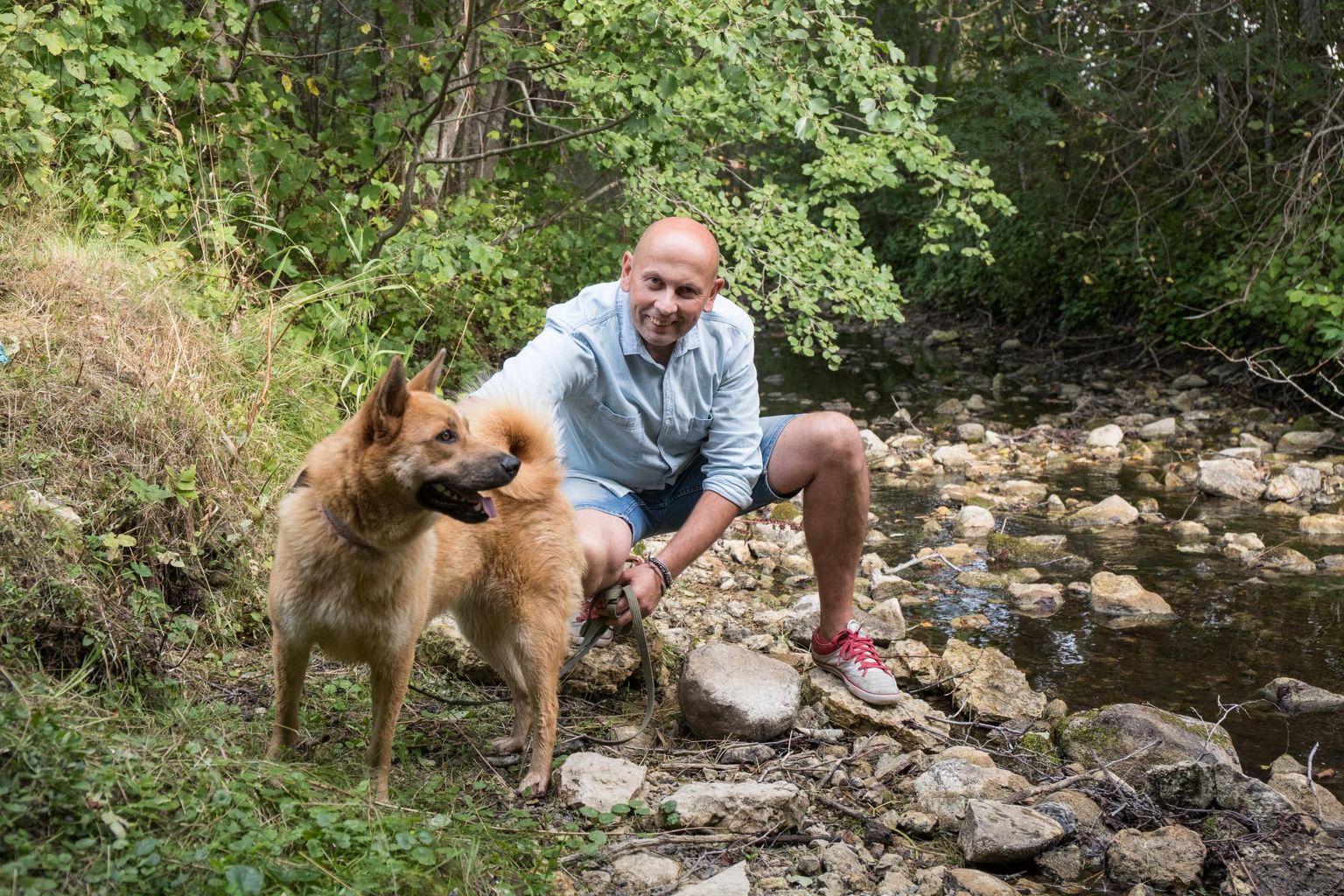Postimehe karikaturist Urmas Nemvalts oma pere uusima liikme, varjupaigast võetud kaheaastase koera Bibiga kodu lähedal Angerja oja kaldal.