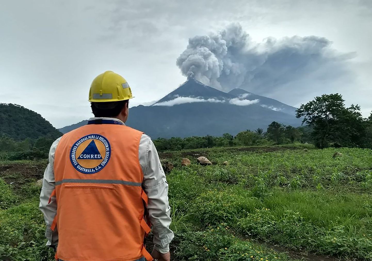Päästetöötaja vaatamas Guatemala Fuego vulkaani suunas
