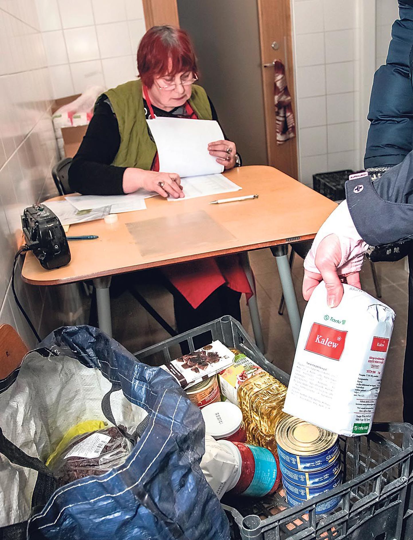 Toidupanga vabatahtlik Sirje Laurimäe kontrollib nimekirja, enne kui toidukraami kätte annab.